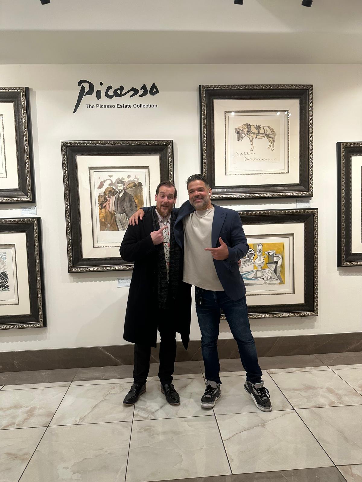 Jason Perez with an artist in a gallery setting near framed Picasso works
